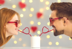 Beautiful Couple enjoying their drinks together through a heart shaped straw dipped in glass