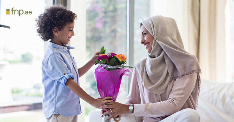 A cute boy giving yellow flower bouquet to his mother