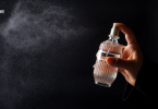Hand spraying perfume mist from a bottle into the air