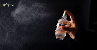 Hand spraying perfume mist from a bottle into the air