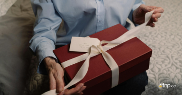 A person unwrapping red colour gift box