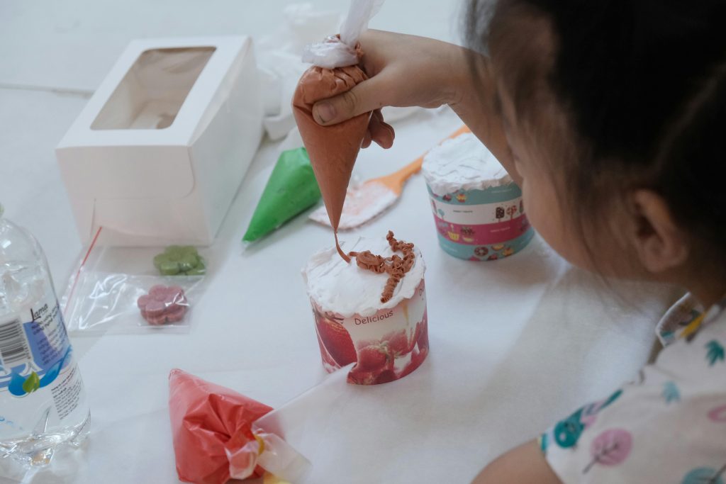 A small girl decorating mini cake