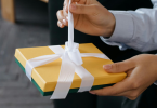 A person opening white ribbon wrapped on the gift box