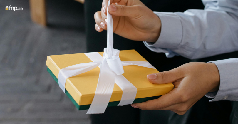 A person opening white ribbon wrapped on the gift box
