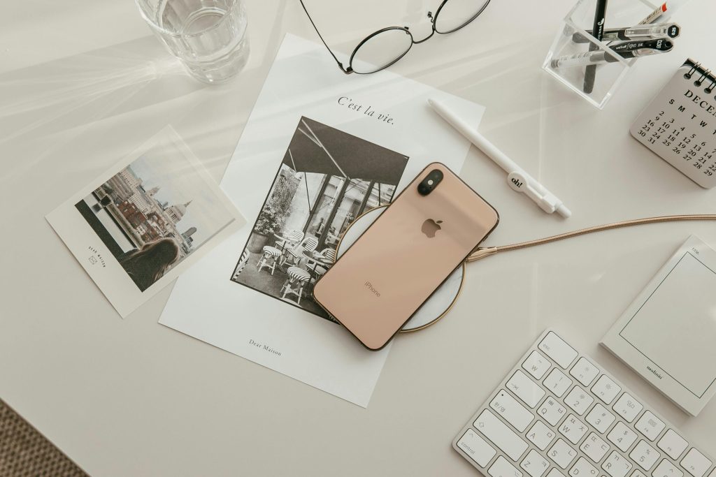 A Gold Colour Iphone being charge via wireless charger on office desk