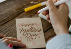 A Girl writing Happy Mother's Day wish on card