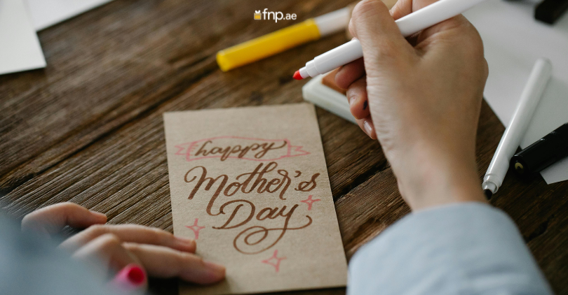 A Girl writing Happy Mother's Day wish on card