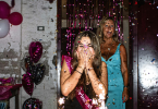 Women walking into a room decorated with balloons and confetti surprises