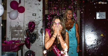 Women walking into a room decorated with balloons and confetti surprises